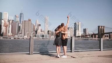 快乐的欧洲游客夫妇站在拥抱，举起双臂欣赏史诗般的曼哈顿景观在纽约，美国慢动作。